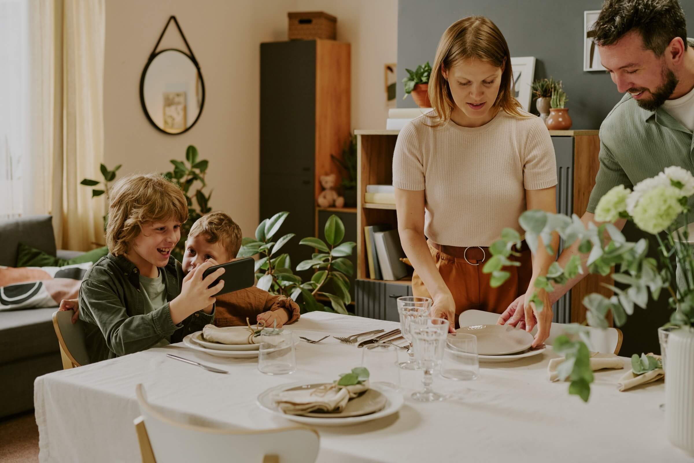 Brüder machen ein Handyfoto, während die Familie den Tisch deckt