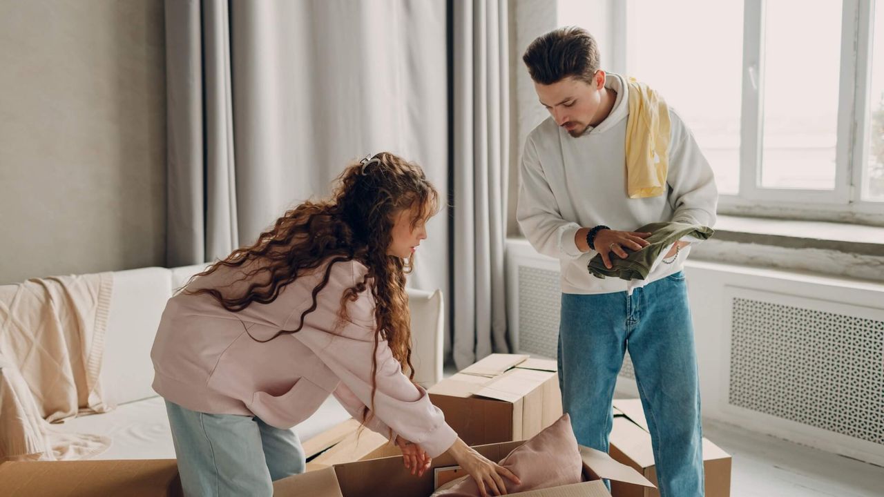 Paar packt Umzugskartons in einem neuen Zuhause aus