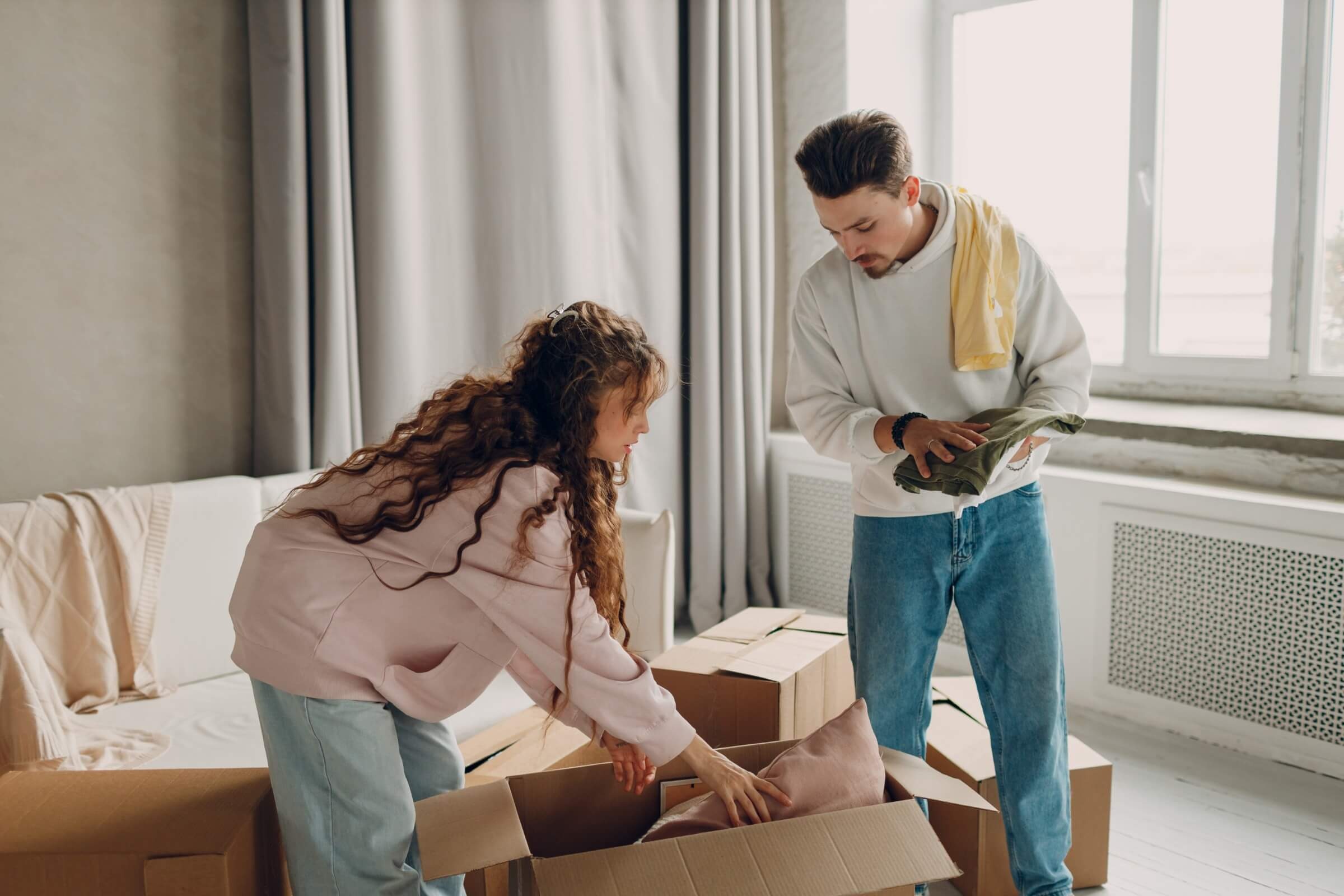 Paar packt Umzugskartons in einem neuen Zuhause aus