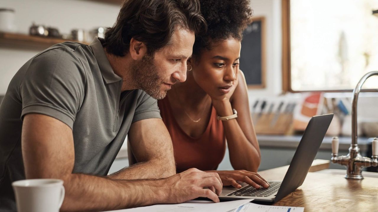 Paar nutzt gemeinsam einen Laptop in der heimischen Küche