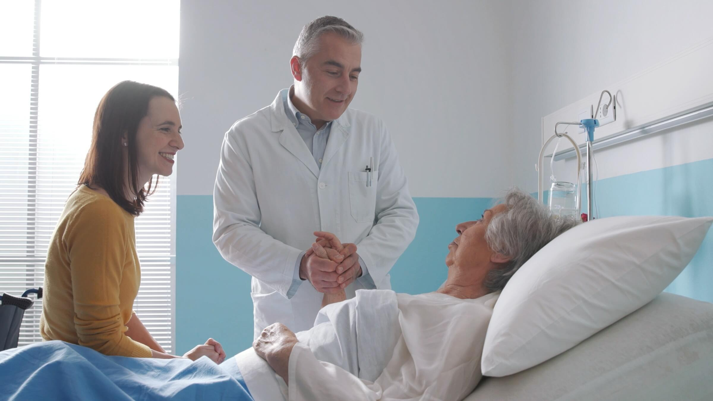 Arzt besucht einen älteren Patienten im Krankenhausbett