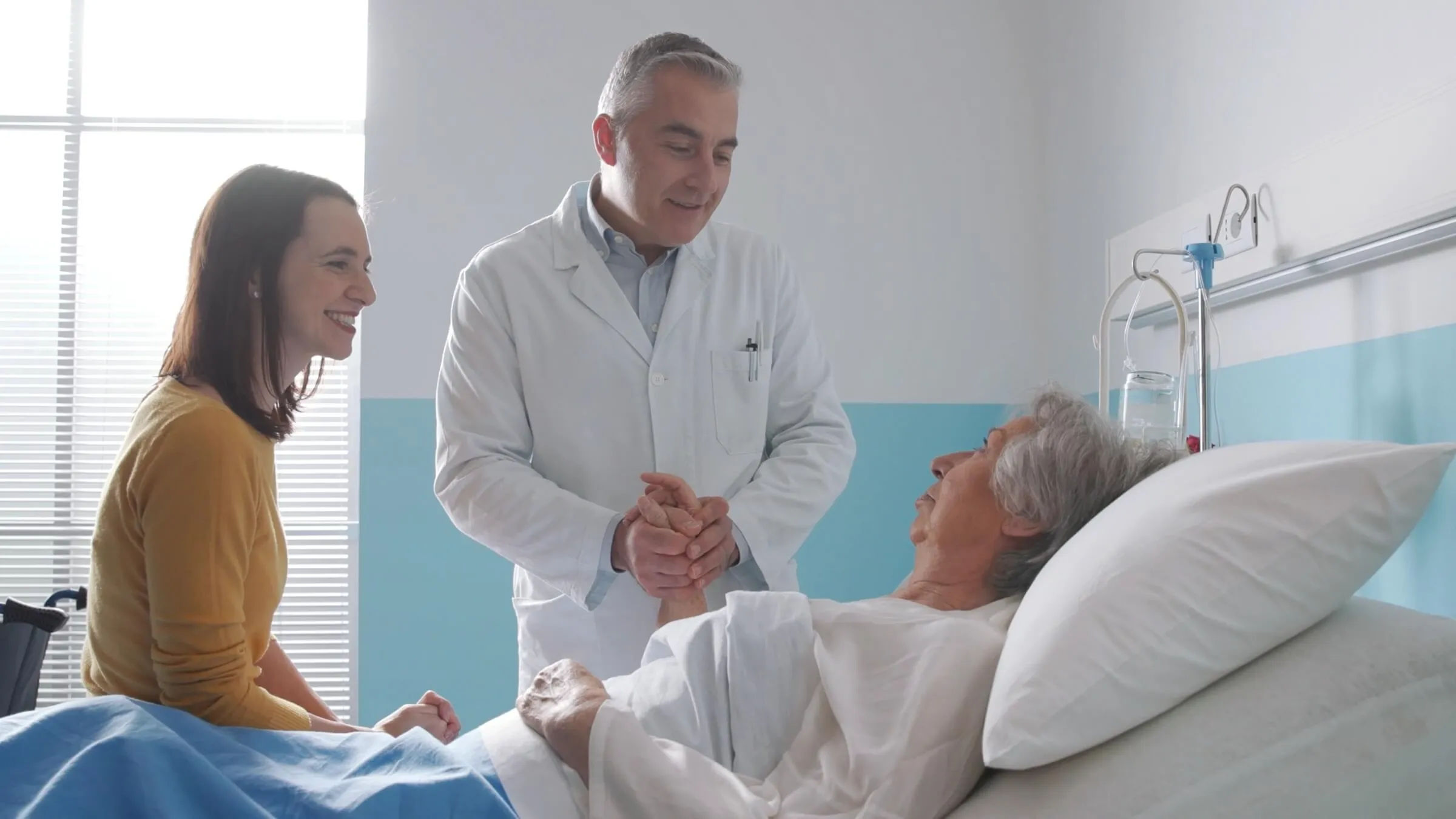 Arzt besucht einen älteren Patienten im Krankenhausbett
