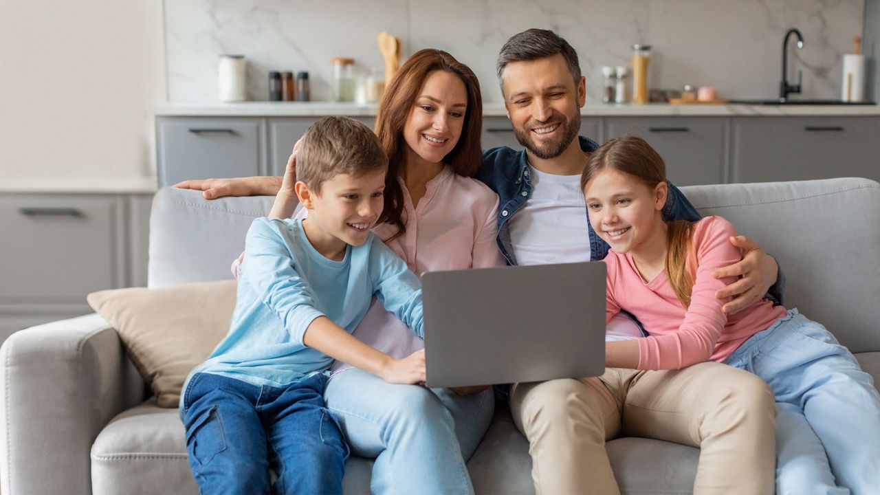 Family relaxing on sofa using laptop together