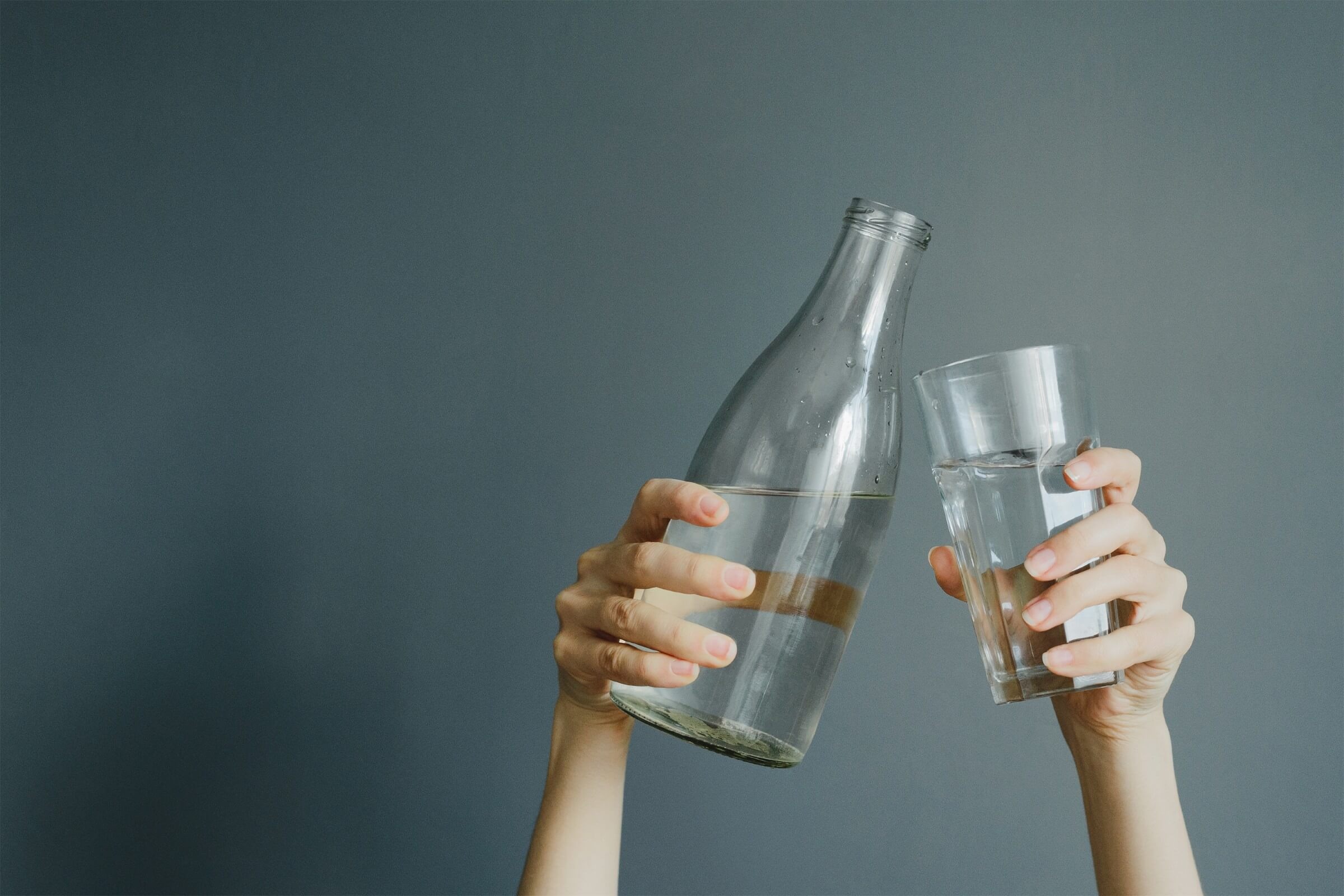 Hände halten ein Glas und eine Wasserflasche