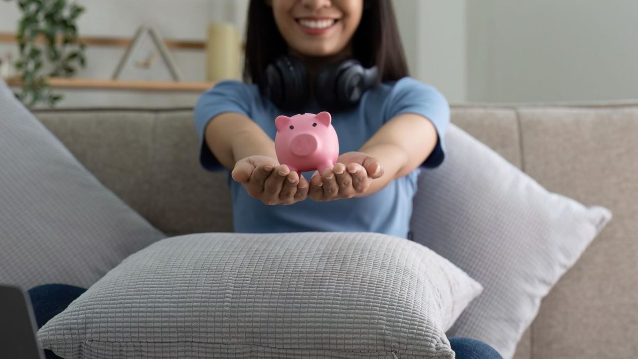 Hände einer Frau halten ein rosa Sparschwein – Konzept des Sparens und der finanziellen Vorsorge