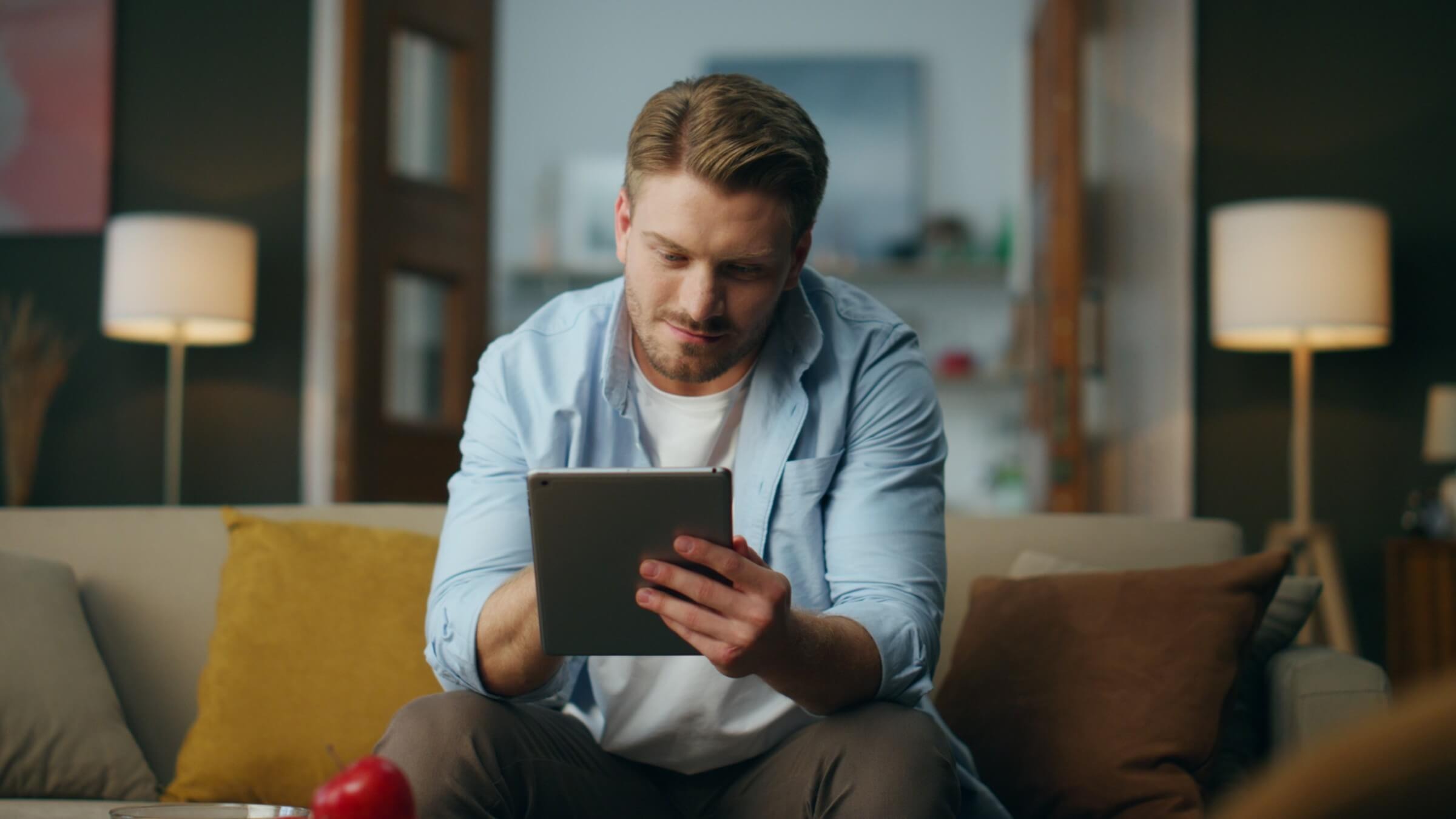 Mann entspannt sich zu Hause auf der Couch mit einem Tablet