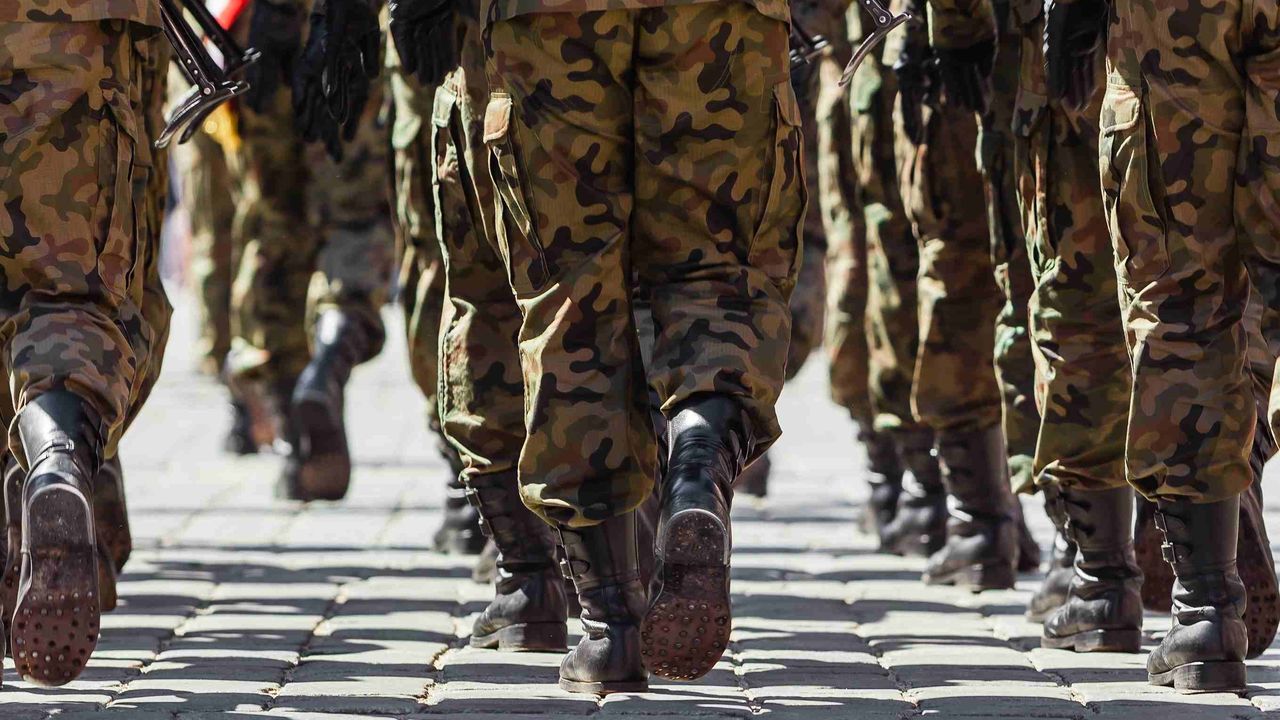 Militärkadetten marschieren in Tarnuniformen auf einem Gelände