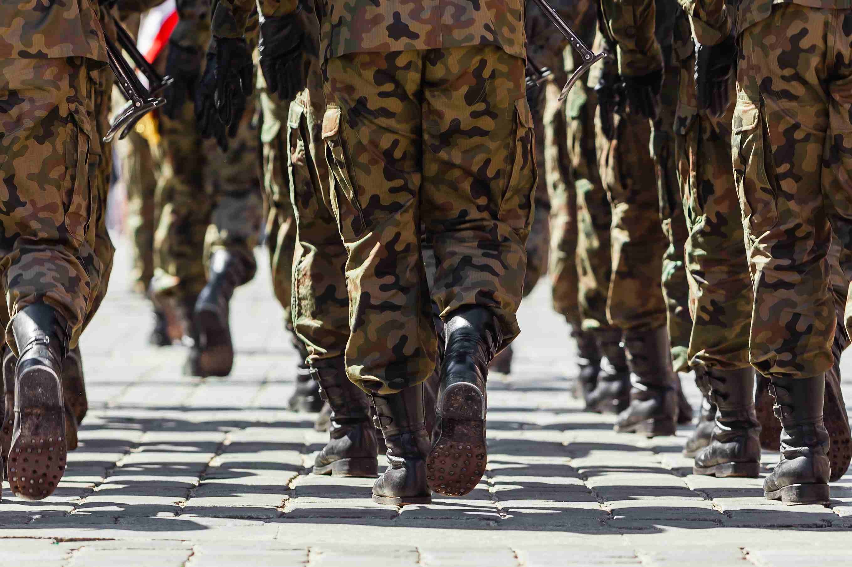 Militärkadetten marschieren in Tarnuniformen auf einem Gelände