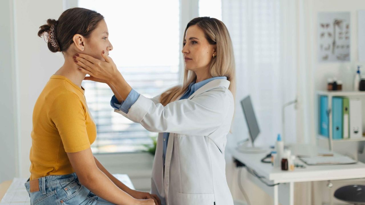 Patient wird in der Arztpraxis am Hals untersucht