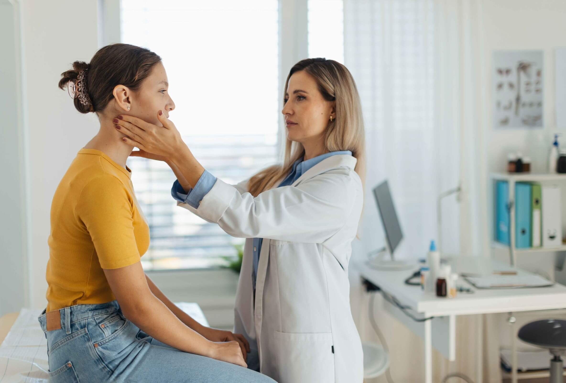 Patient wird in der Arztpraxis am Hals untersucht