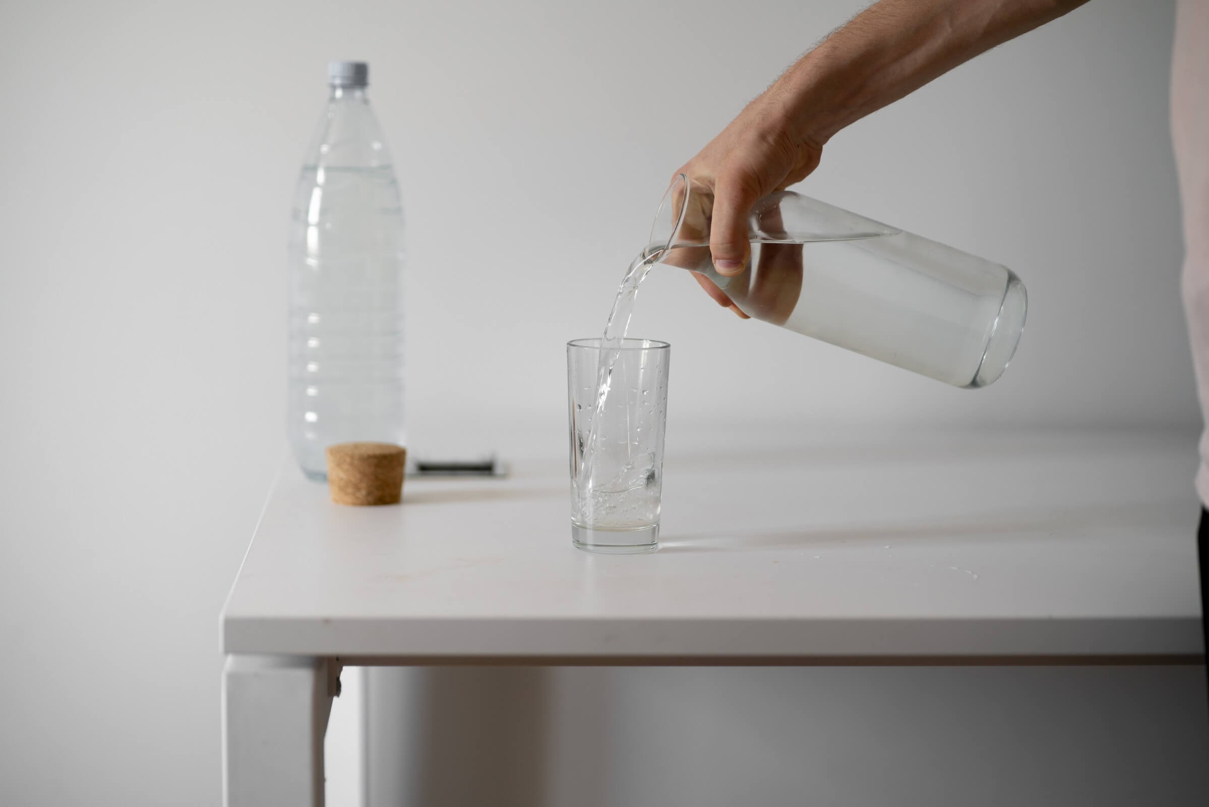 Person gießt erfrischendes Wasser in ein Glas in Innenräumen