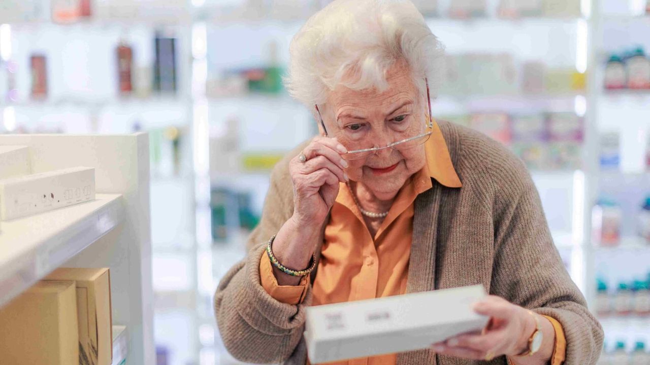 Seniorin liest ein Etikett im Apothekengang