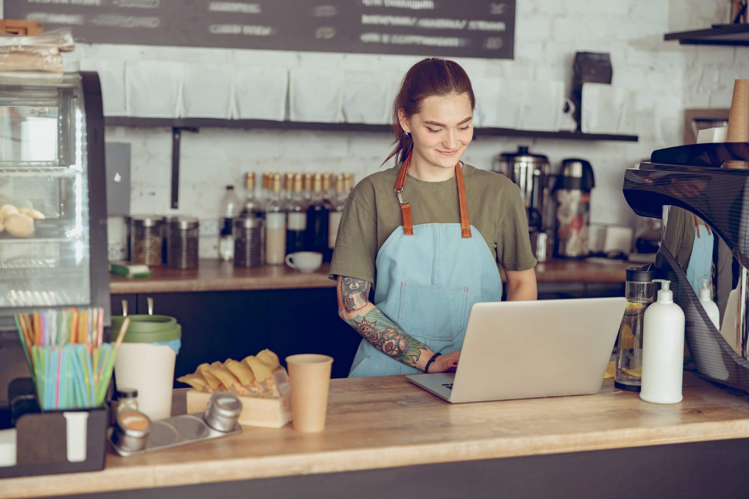 Lächelnde Barista arbeitet mit einem Notebook im Café