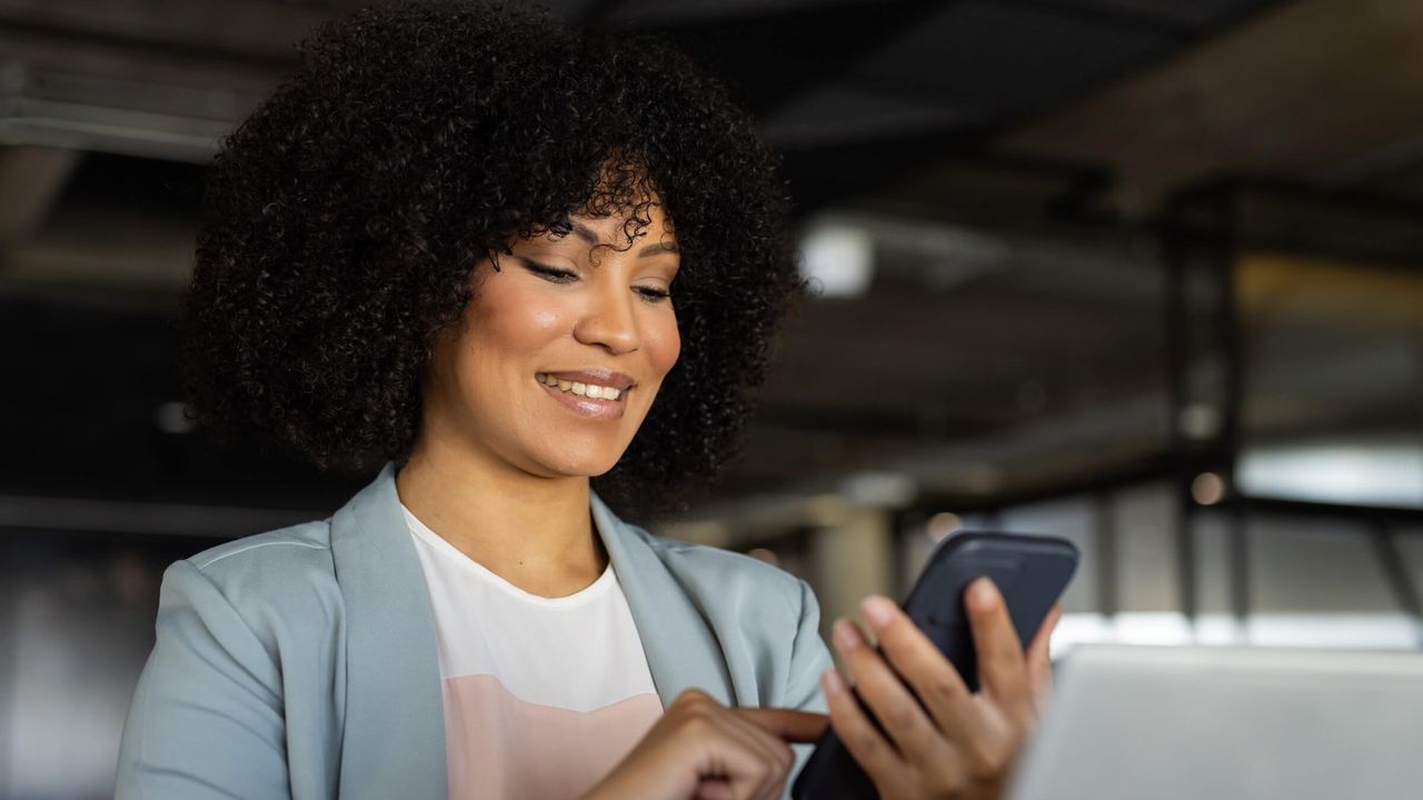 Geschäftsfrau arbeitet lächelnd mit dem Smartphone