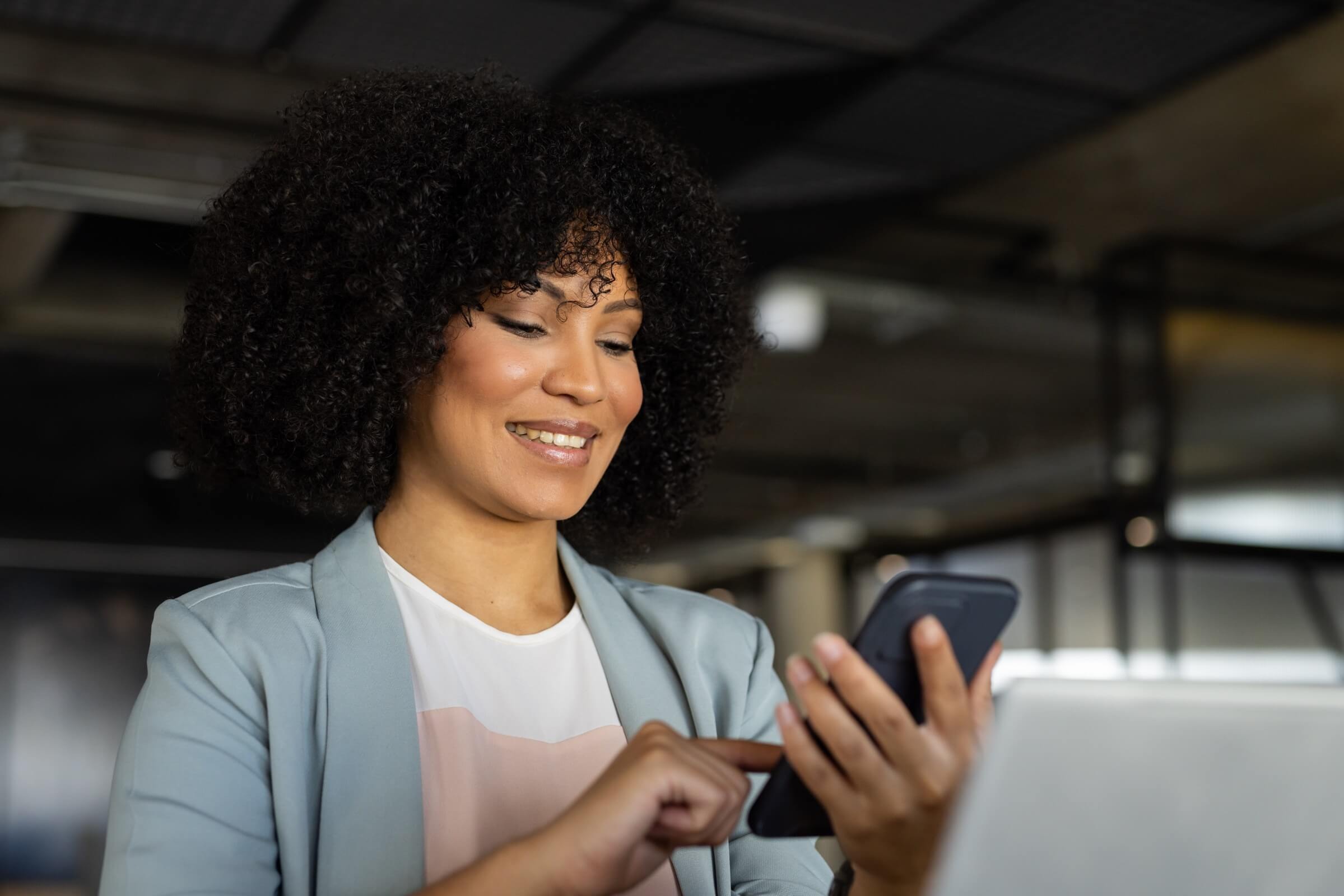 Geschäftsfrau arbeitet lächelnd mit dem Smartphone