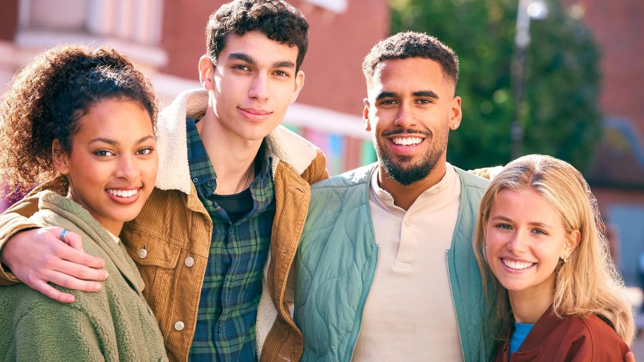 Lächelnde junge Freunde vor einem Backsteingebäude