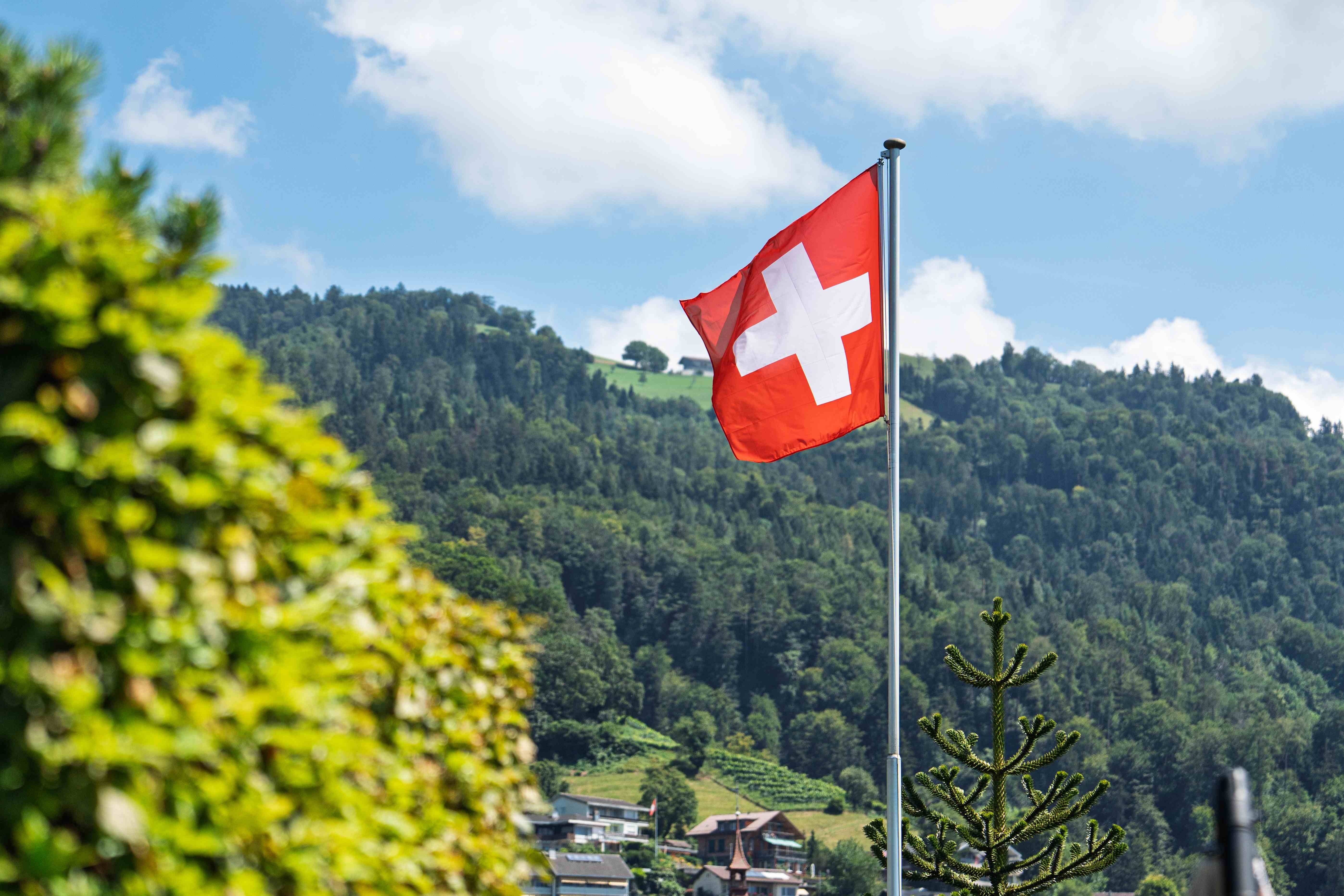 Schweizer Flagge weht vor einer Bergkulisse