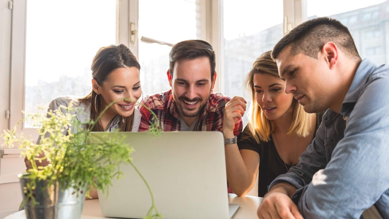 Team arbeitet gemeinsam an einem Laptop in einem hellen Büro