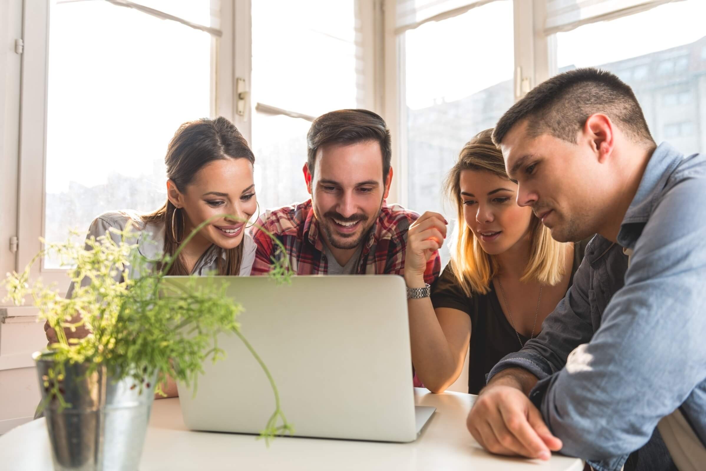Team arbeitet gemeinsam an einem Laptop in einem hellen Büro