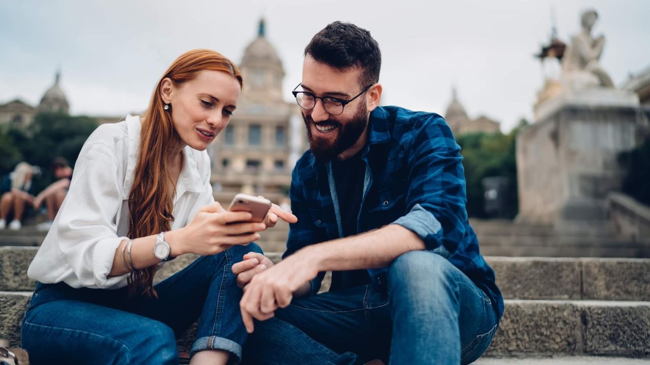 Junge Erwachsene schauen in der Stadt auf ein Smartphone