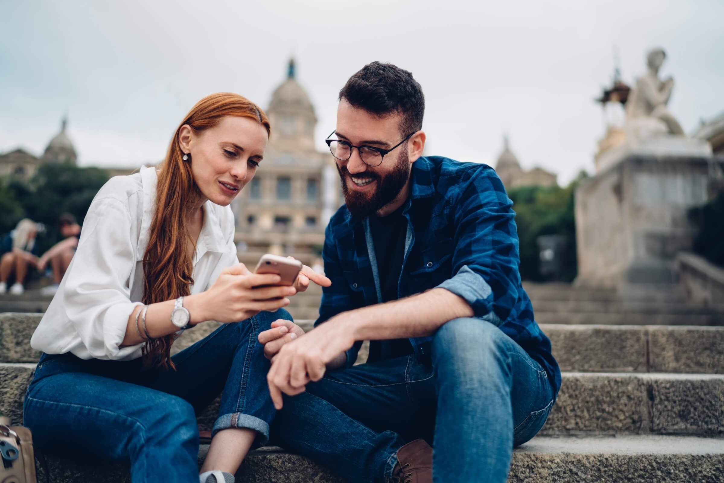 Junge Erwachsene schauen in der Stadt auf ein Smartphone