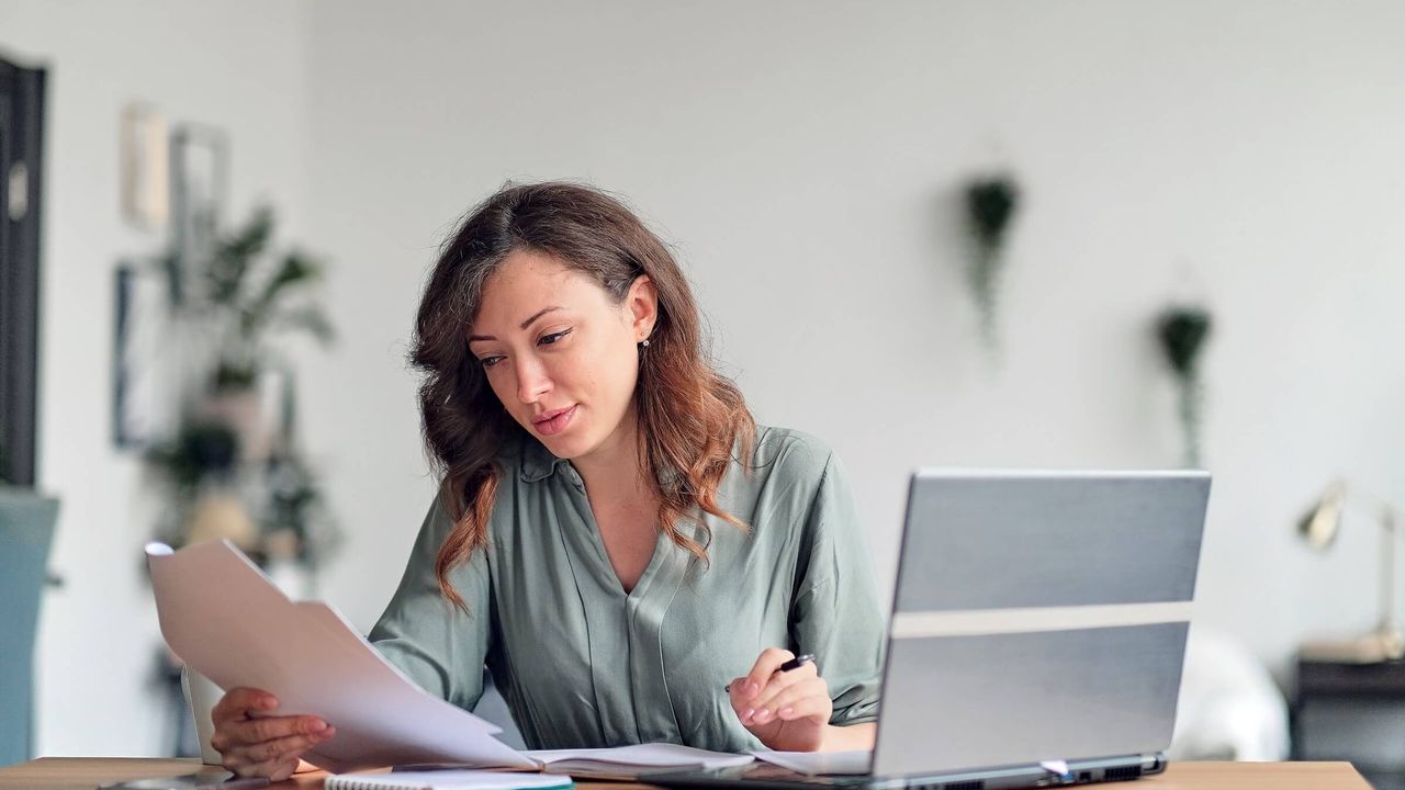 Junge Frau arbeitet im Homeoffice und liest einen Vertrag