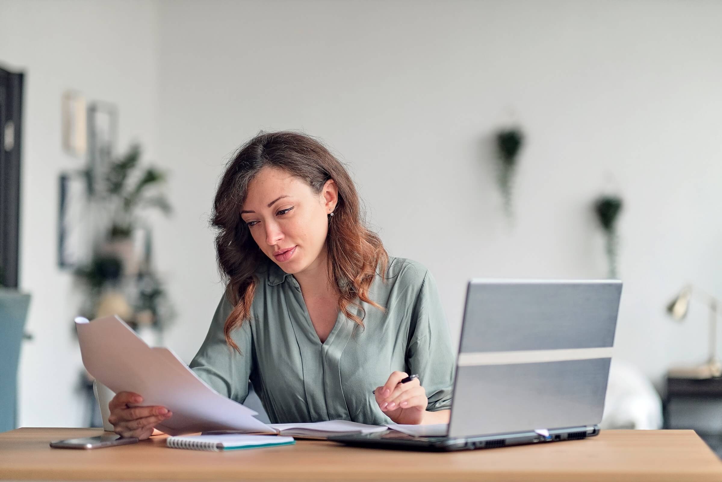 Junge Frau arbeitet im Homeoffice und liest einen Vertrag